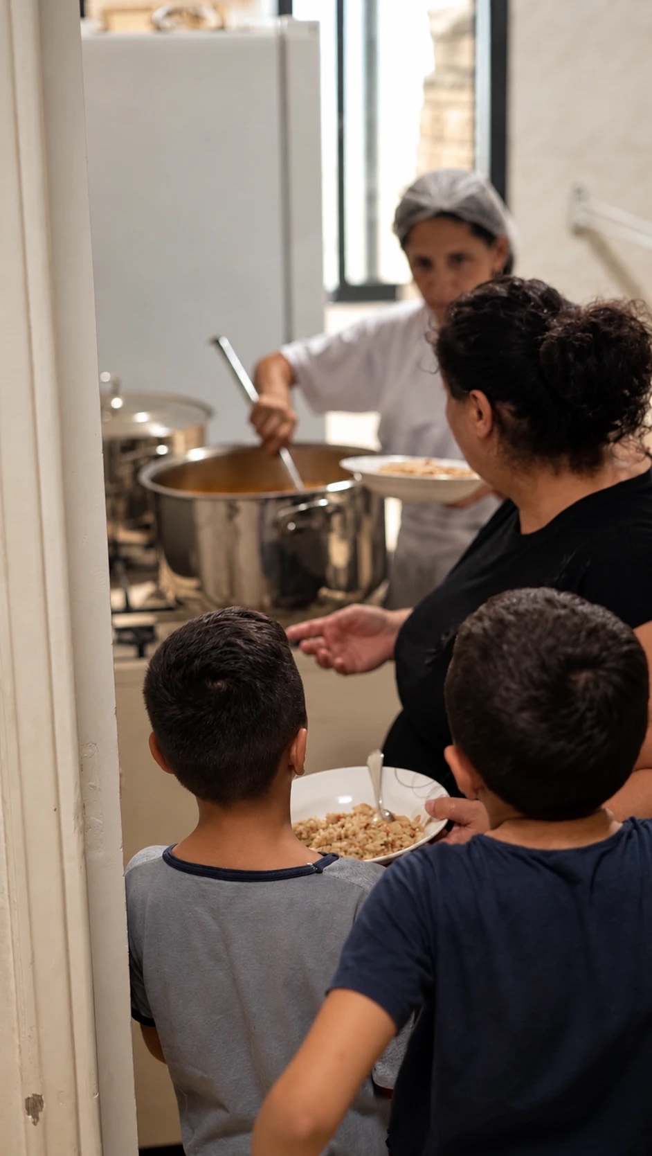 A cook serving rice to children at the center